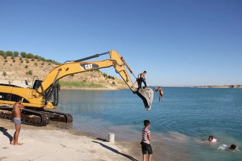İş makinesi serinleyen çocukların eğlencesine ortak oldu

